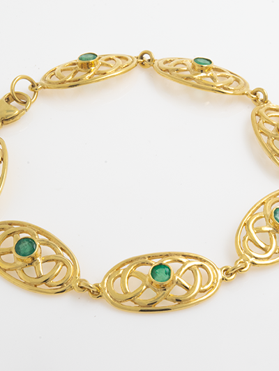 14k Gold Celtic Bracelet featuring intricate knot designs with vivid green emeralds, set in glowing 14k gold.